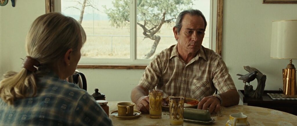 Ed Tom Bell (Tommy Lee Jones) sitting at the kitchen table with his wife Loretta Bell (Tess Harper) in No Country for Old Men.